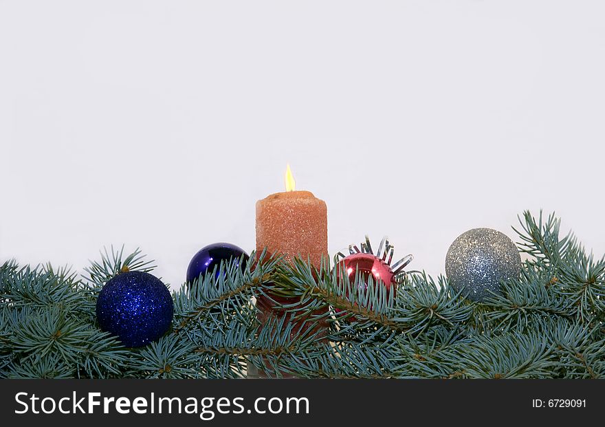 Branches of a blue spruce with Christmas toys and burning candle