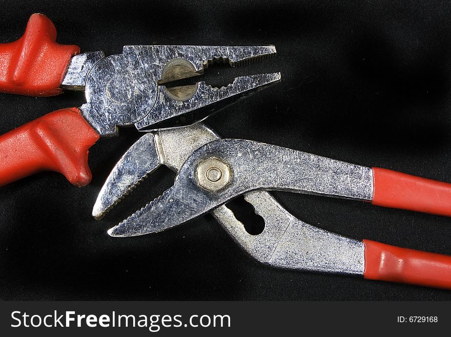 Pliers with red neck on a black background. Pliers with red neck on a black background