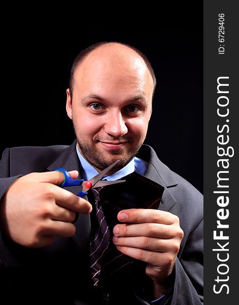 Man in a business suit scissors the tie, on a black background. Man in a business suit scissors the tie, on a black background