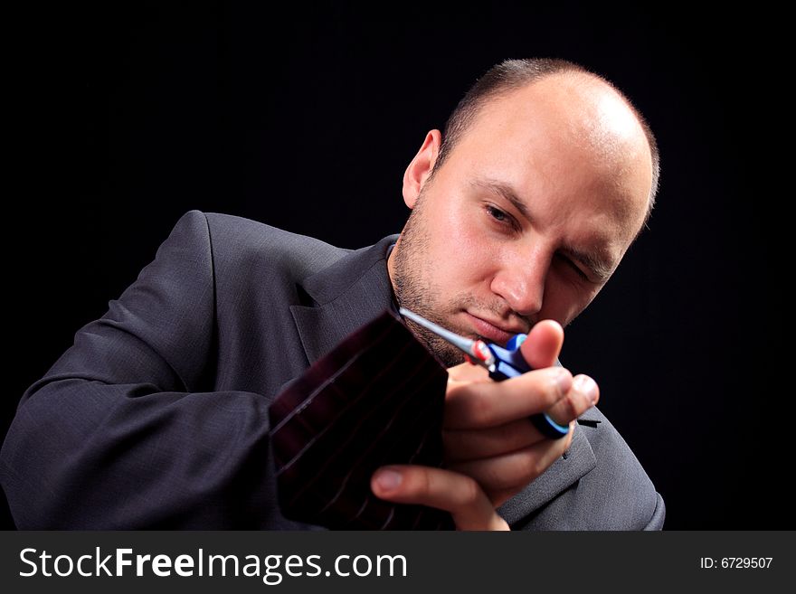 Man in a business suit scissors the tie, on a black background. Man in a business suit scissors the tie, on a black background