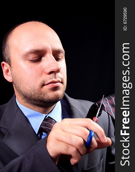 Man in a business suit scissors the tie, on a black background. Man in a business suit scissors the tie, on a black background