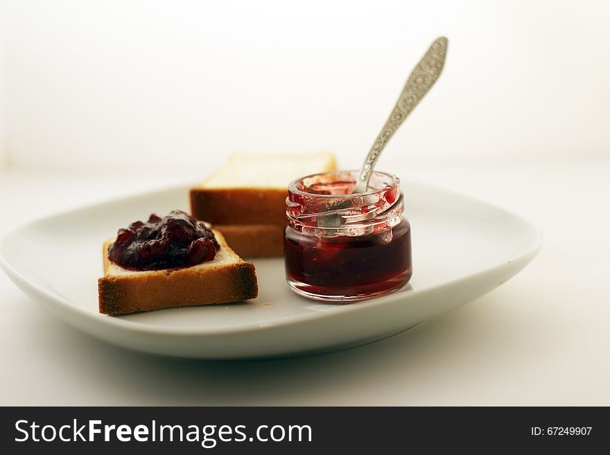 A mason jar of jam and bread on a white plate