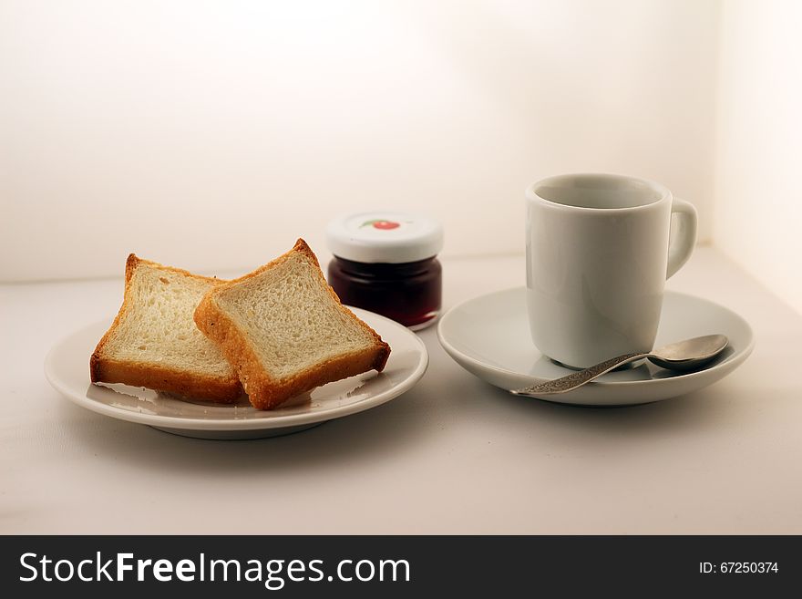 A mason jar of jam, cup of tea and bread on a white plate. A mason jar of jam, cup of tea and bread on a white plate