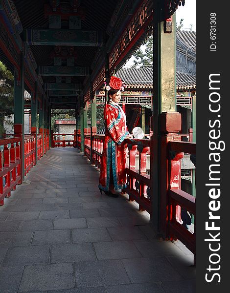 A girl in Chinese ancient dress stands in the long corridor of the royal garden. Chinese on the fan is meant and missed. A girl in Chinese ancient dress stands in the long corridor of the royal garden. Chinese on the fan is meant and missed.