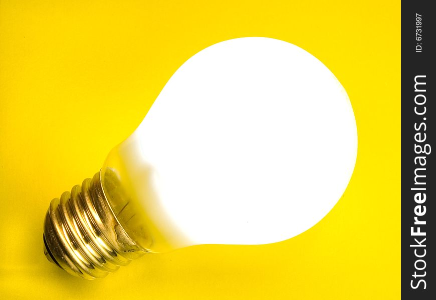 A bright shining light bulb on a yellow background. A bright shining light bulb on a yellow background.