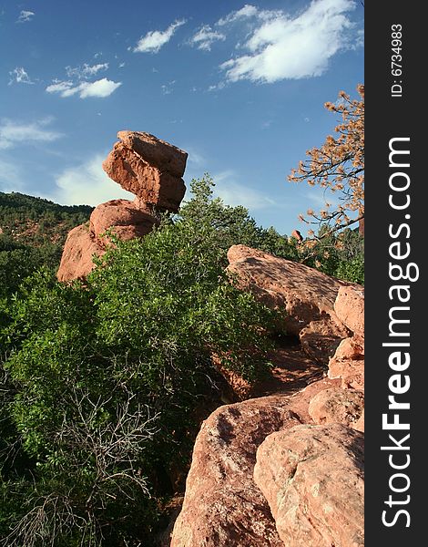 Large red rock balanced on a small area on another rock in the garden of the gods park. Large red rock balanced on a small area on another rock in the garden of the gods park.