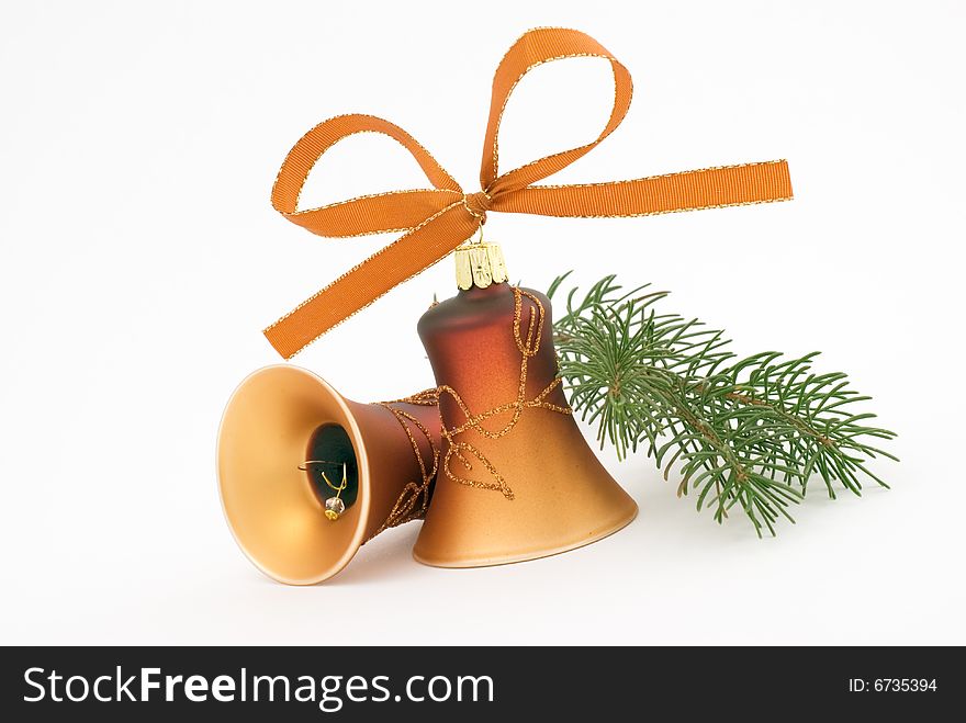 Two golden christmas bells on the white background with spruce twig