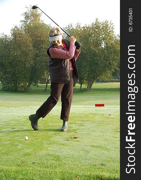 Female golfer teeing off on the green