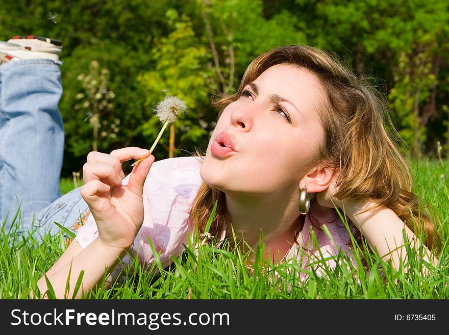 Young girl blowing on the dandelion