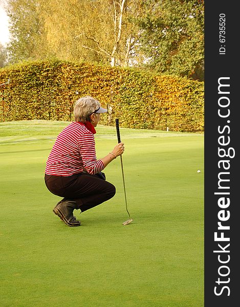 Female golfer checking distance on the green. Female golfer checking distance on the green