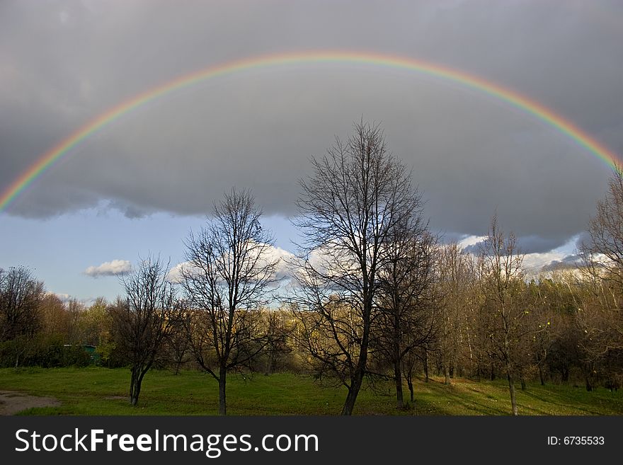 The cloudy sky and autumn rainbow above forest. The cloudy sky and autumn rainbow above forest.