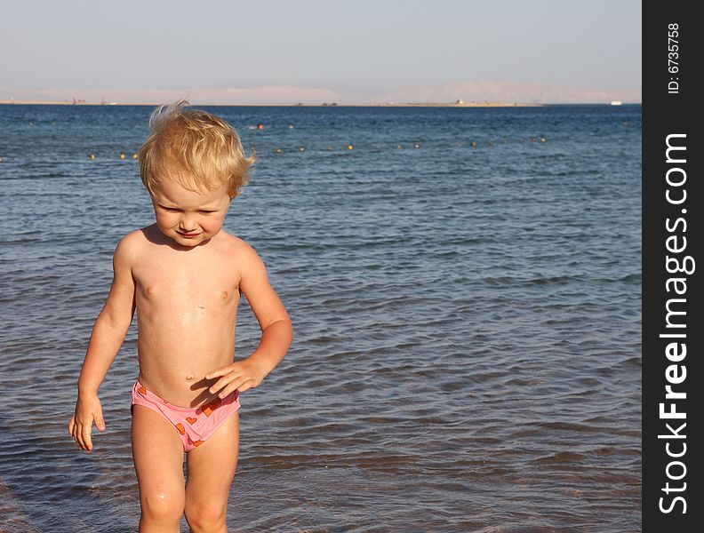 The little girl against a background of blue sky and sea. The little girl against a background of blue sky and sea.