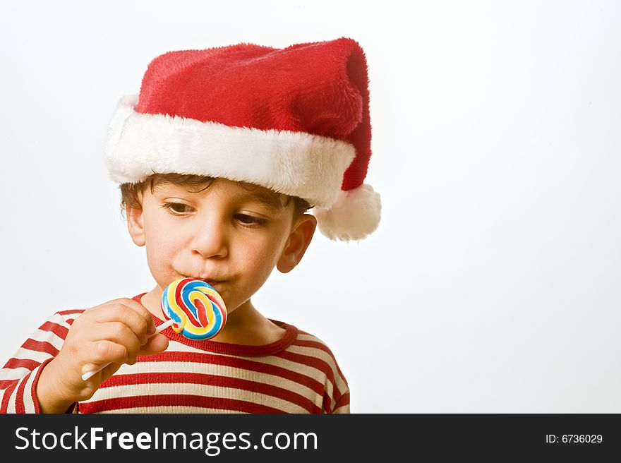 Child with christmas hat and lollipop. Child with christmas hat and lollipop