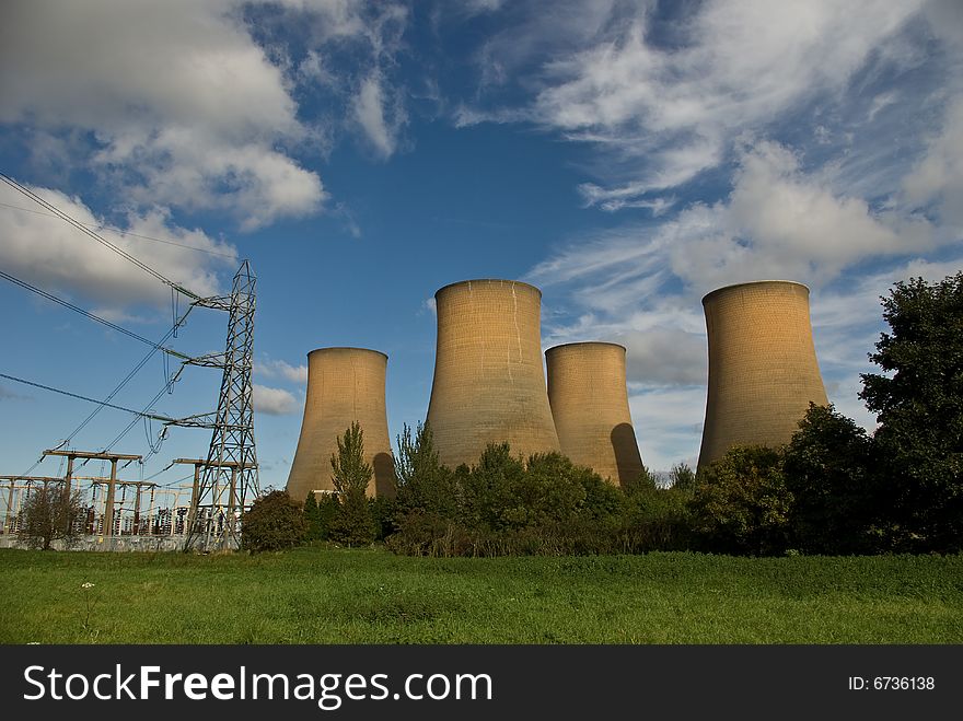 The cooling towers of a power station against a blue sky. The cooling towers of a power station against a blue sky