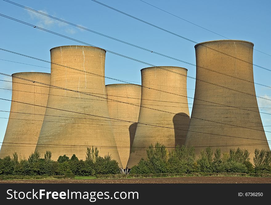 The cooling towers of a power station against a blue sky. The cooling towers of a power station against a blue sky