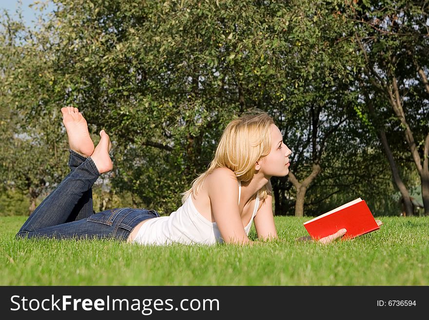 Young blonde reads book in the park