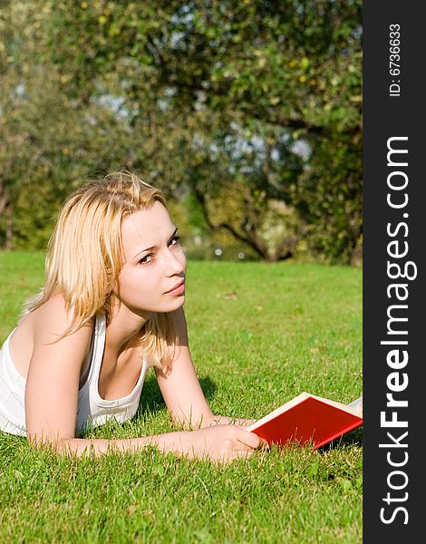 Young blonde reads book in the park