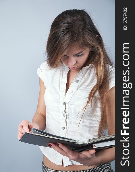 Young student girl looking to textbook on grey background