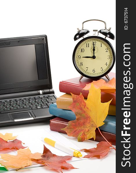 Pile of books, notebook, alarm clock and autumn leaves on a white background. Pile of books, notebook, alarm clock and autumn leaves on a white background.