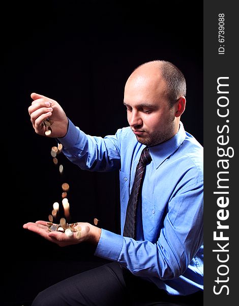 Man in a shirt and a tie fills coins, on a black background. Man in a shirt and a tie fills coins, on a black background