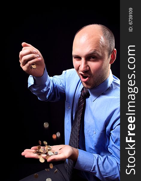 Man in a shirt and a tie fills coins, on a black background. Man in a shirt and a tie fills coins, on a black background