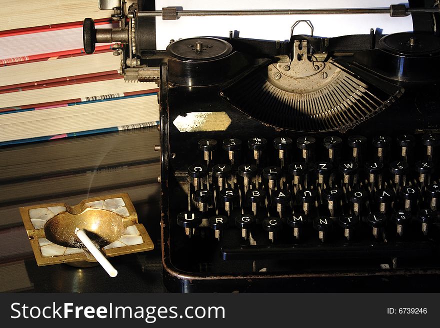 Antique manual typewriter with books and ash-tray. Antique manual typewriter with books and ash-tray