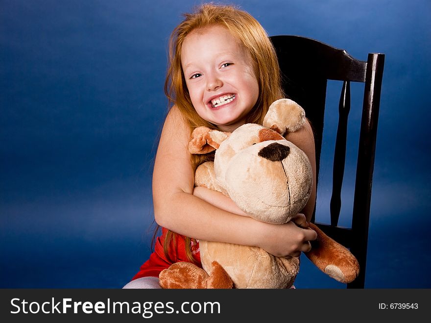 Beautiful ginger girl with a toy against blue background. Beautiful ginger girl with a toy against blue background