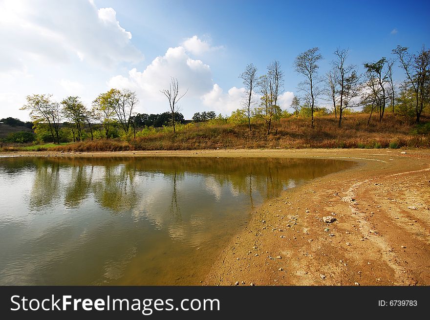 Lake with trees and blue cloudy sky. Lake with trees and blue cloudy sky