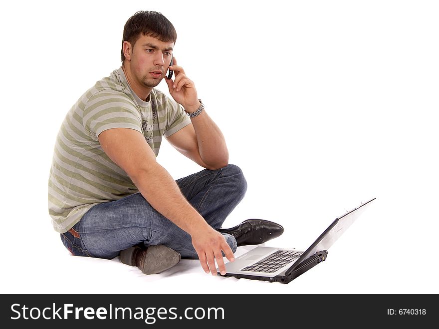 Young hadnsome guy working with laptop and talking over mobile phone, isolated on white background. Young hadnsome guy working with laptop and talking over mobile phone, isolated on white background