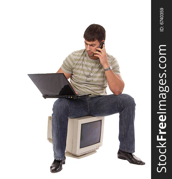 Contemporary young guy sitting on an old-fashioned computer, working with laptop and talking over a mobile phone, isolated on white background. Contemporary young guy sitting on an old-fashioned computer, working with laptop and talking over a mobile phone, isolated on white background