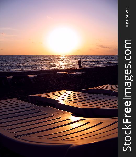 Chaise longues ashore over sunset sky