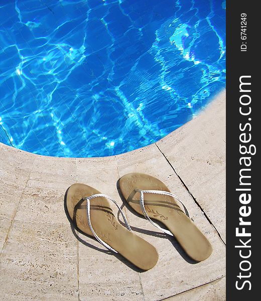 Flip-flops by blue swimming pool