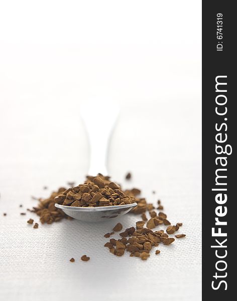 Coffee spoon loaded with granules. Shallow depth of field. White background. Space for copy.