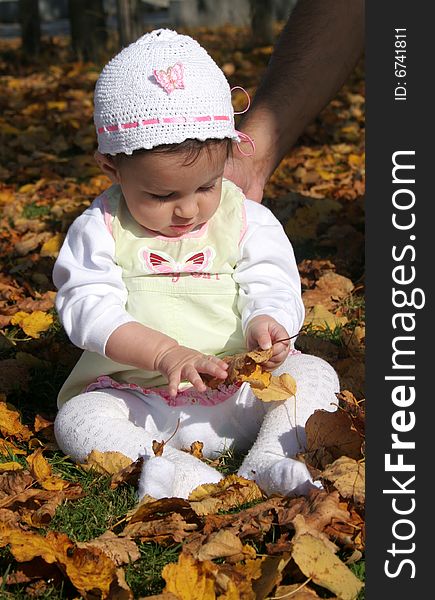 Cute baby girl  playing in the park on a sunny autumn day. Cute baby girl  playing in the park on a sunny autumn day