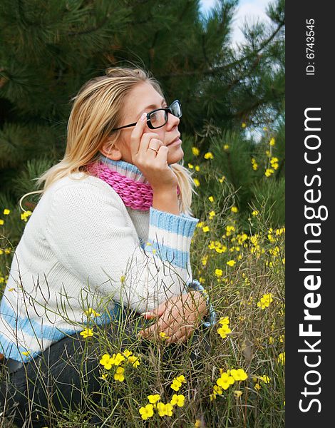 The girl sits on a lawn   in an environment of yellow colours. The girl sits on a lawn   in an environment of yellow colours