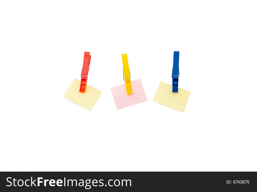 Three pegs holding coloured scratch paper isolated on white. Three pegs holding coloured scratch paper isolated on white
