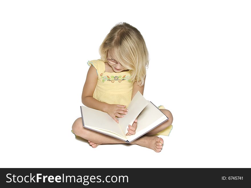 A young blonde girl sitting crosslegged while reading a textbook. Isolated on a white background. A young blonde girl sitting crosslegged while reading a textbook. Isolated on a white background