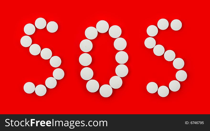 Word SOS made of pills isolated on red background