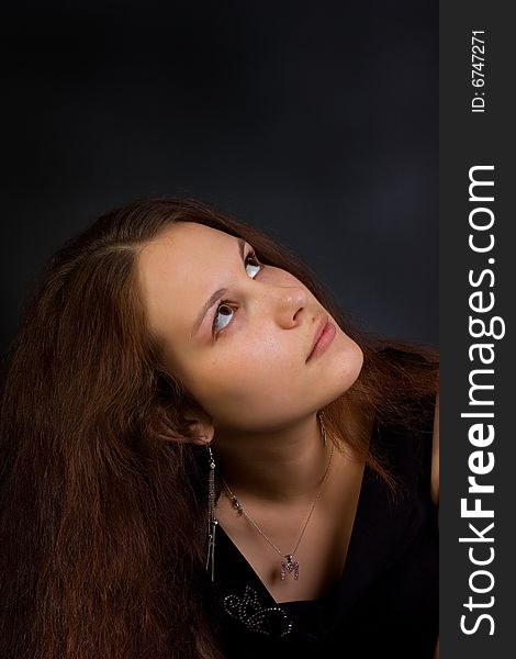 Young woman looking to up. Dark background. Young woman looking to up. Dark background
