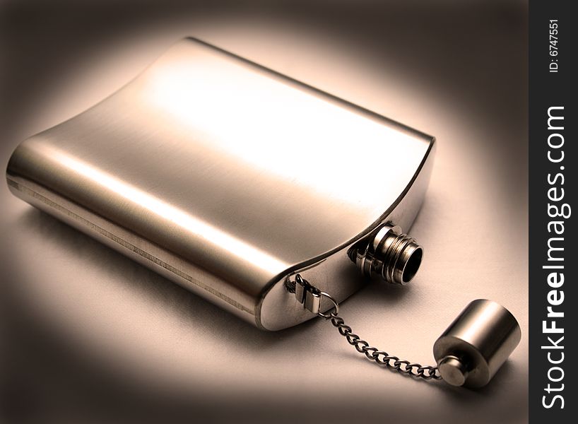 Metal chrome flask lying on its side with the lid off with dark edges