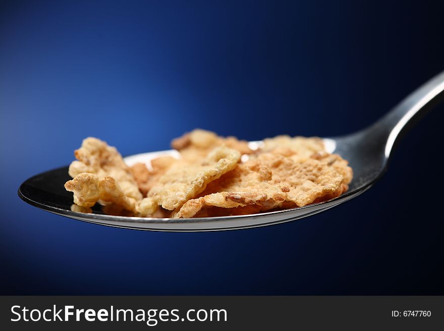 Spoon with cornflakes on blue background. Spoon with cornflakes on blue background