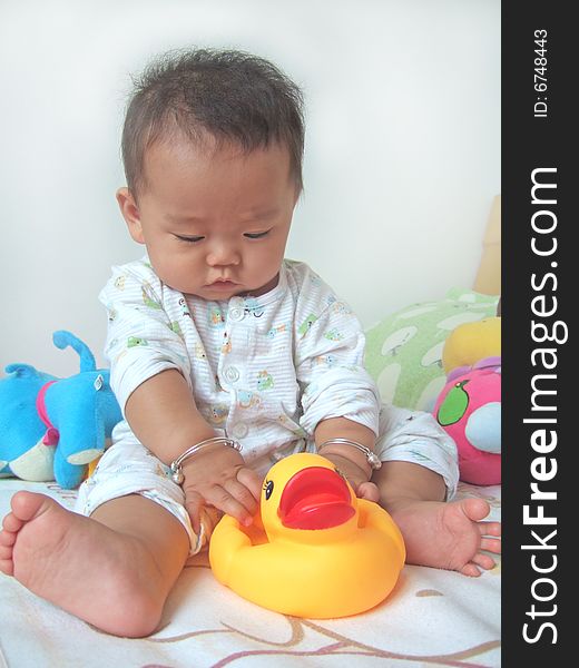 Pretty baby and toy ducks on a bed