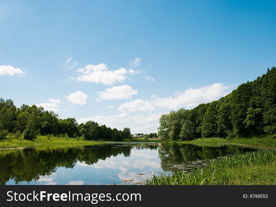 A walk near the lake in a sunny day. Beautiful reflection of the clouds in the lake. Russia, Summer 2008.