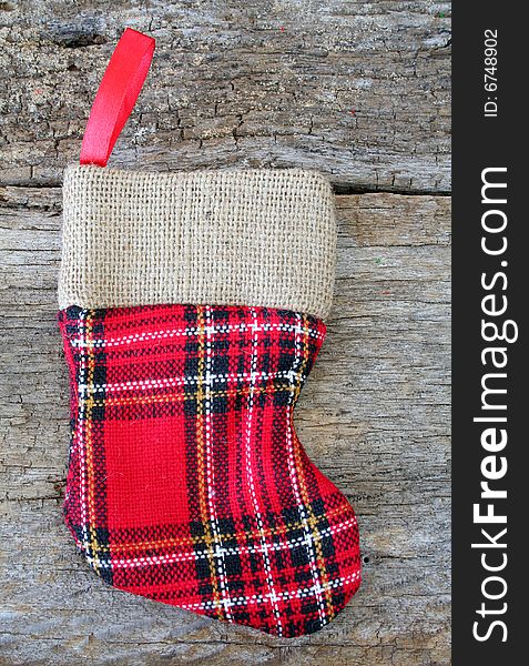 A plaid and burlap Christmas stocking on an old piece of wood to add a rustic look.