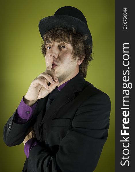 Elegant speaker with purple shirt and bowler hat hushing you. Elegant speaker with purple shirt and bowler hat hushing you