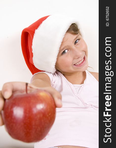 Smiling little girl with Christmas hat showing apple. Smiling little girl with Christmas hat showing apple