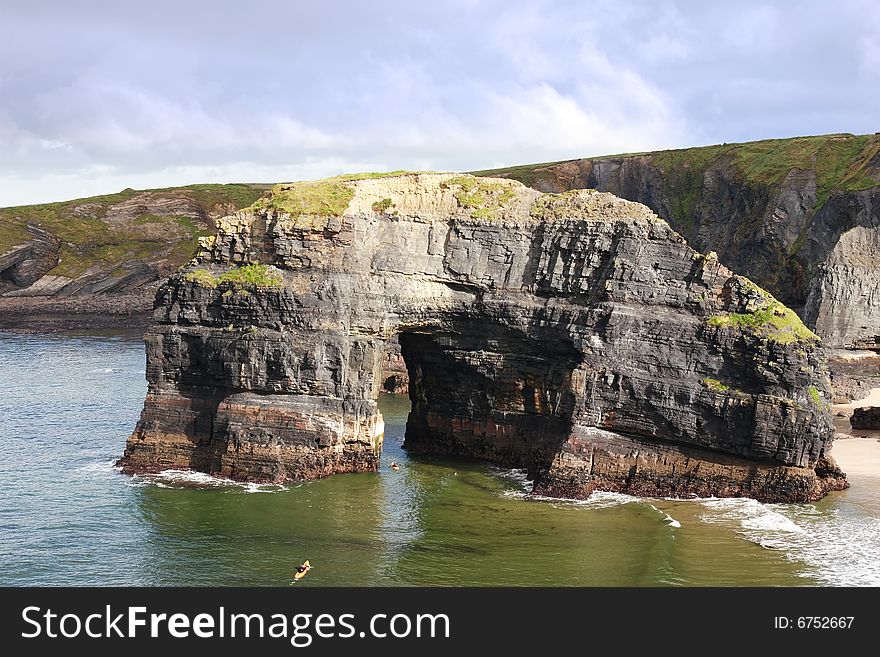 A canoeist at the virgin rock in ballybunion ireland as seen from the cliffs. A canoeist at the virgin rock in ballybunion ireland as seen from the cliffs