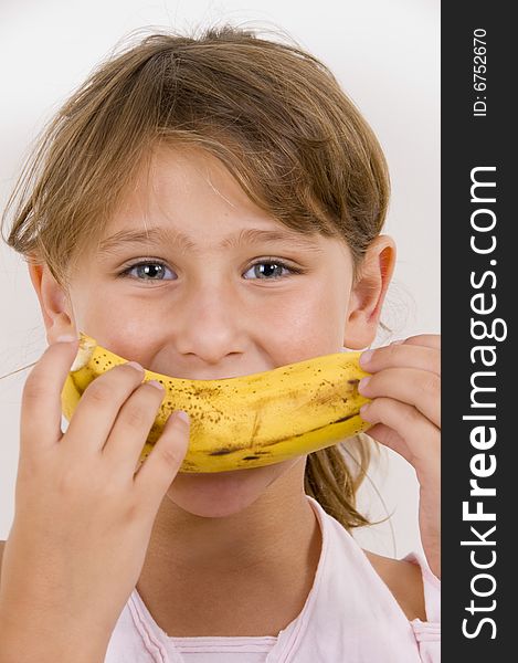 Little girl eating banana and looking at the camera