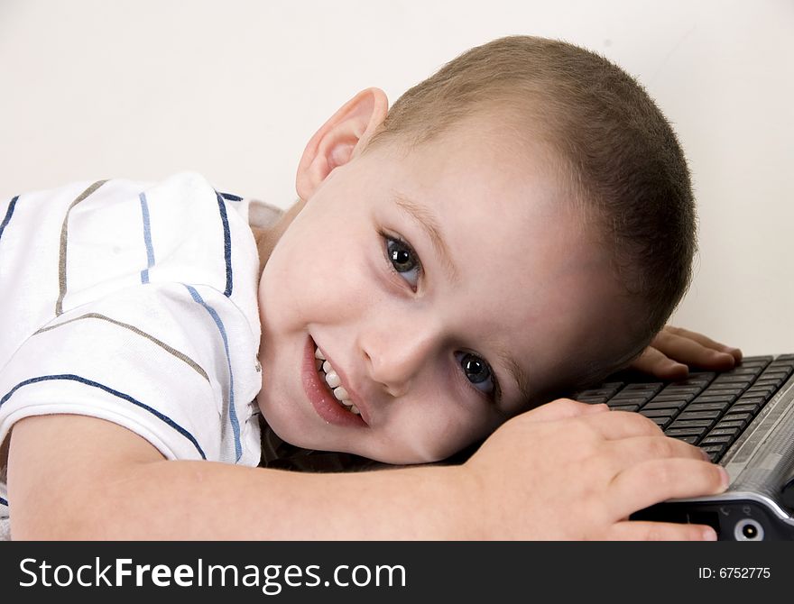 Little boy lying on laptop looking at camera