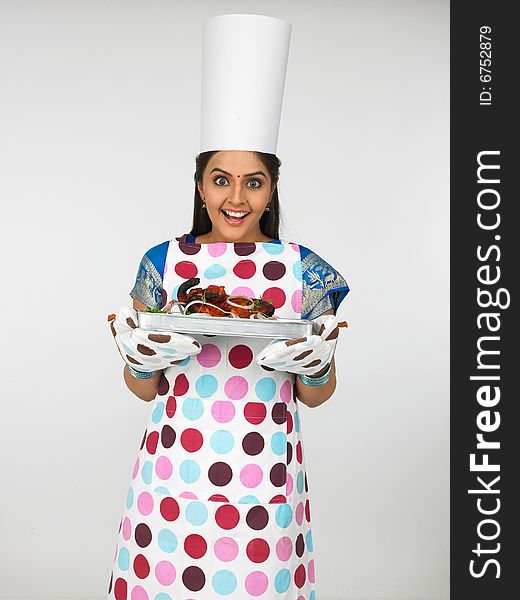 Asian woman of indian origin wearing apron with her baked chicken tandoori. Asian woman of indian origin wearing apron with her baked chicken tandoori